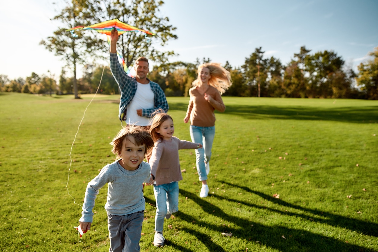 a young boy flying a kite while standing on a lush green field